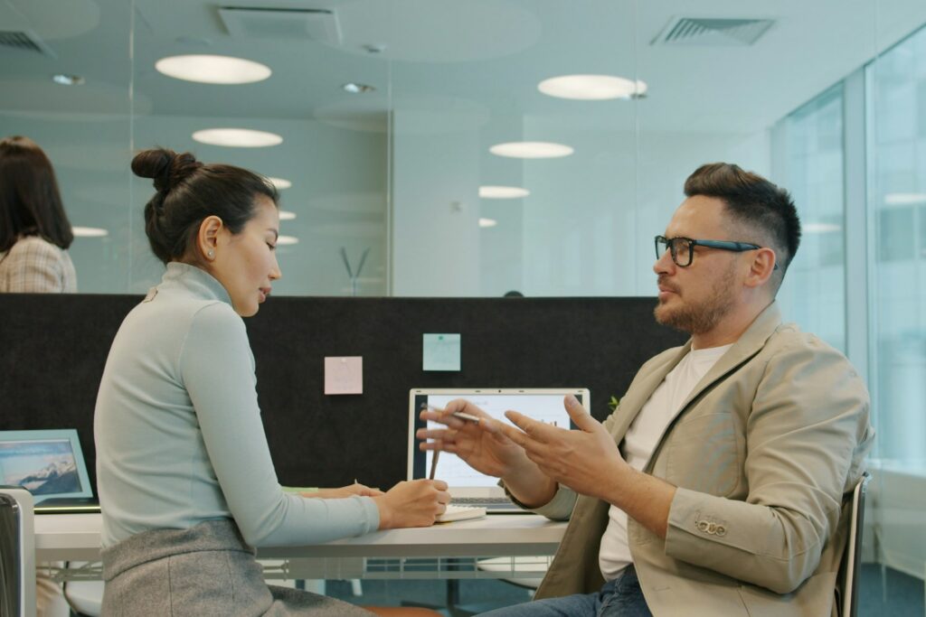 Employer Branding von innen: Zwei Kollegen unterhalten sich in einem modernen Büro über ihre Arbeit