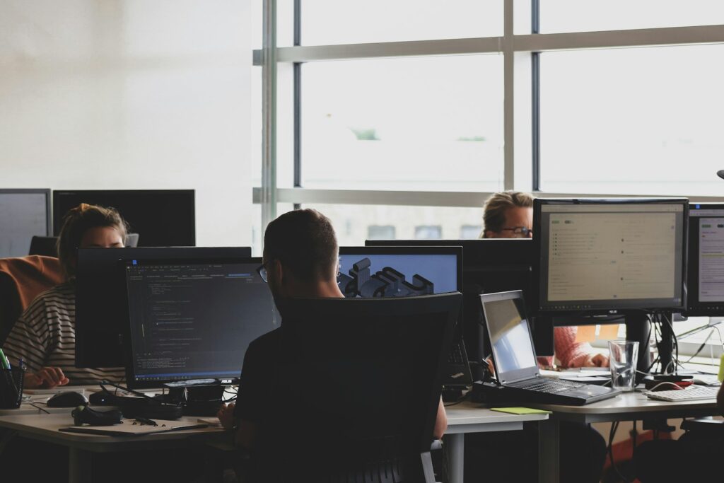 Hybrides Arbeiten fair gestalten: Kollegen sitzen gemeinsam vor einem Monitor