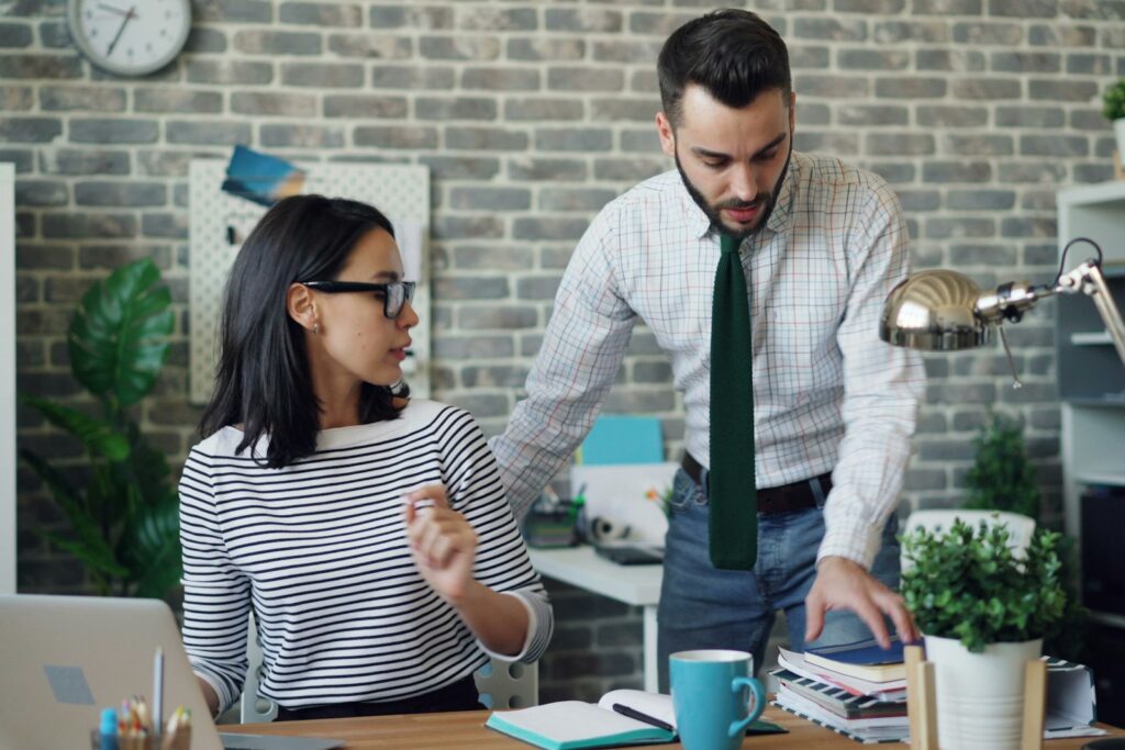 Zwei Kollegen im angespannten Gespräch im Büro: Konflikte im Team beginnen oft im Kleinen