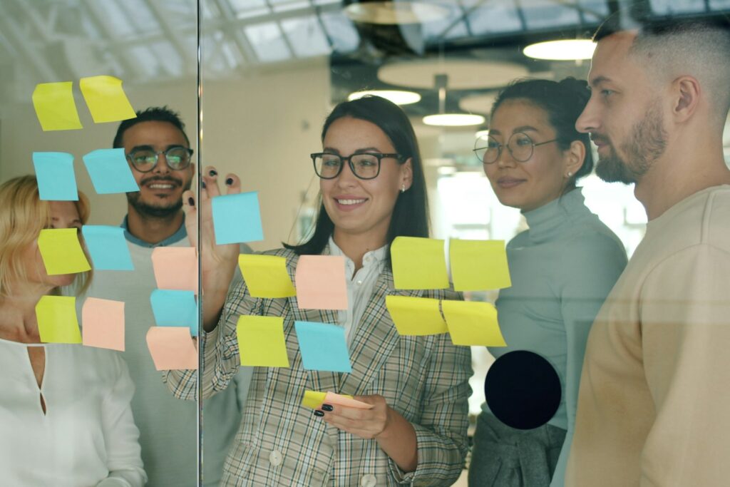 Mitarbeiter motivieren durch Mitgestaltung: Team plant mit Haftnotizen an einer Glaswand