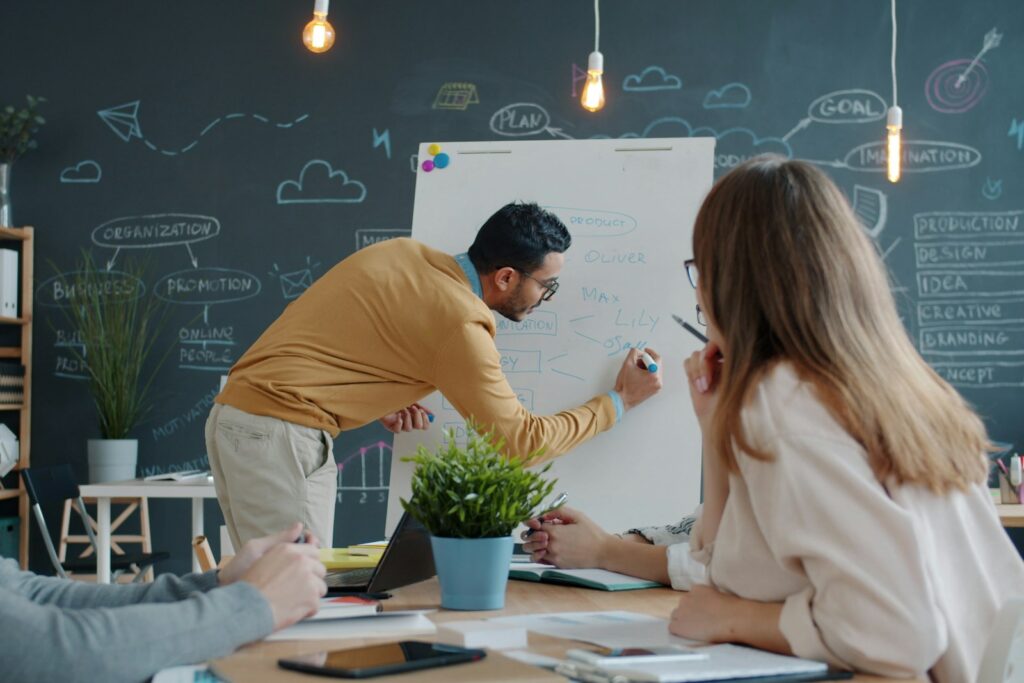Neues Team leiten: Führungskraft stellt sich dem Team im ersten Meeting am Whiteboard vor