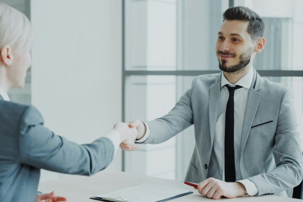 Neues Team leiten: Handschlag zwischen Führungskraft und Teammitglied im Büro