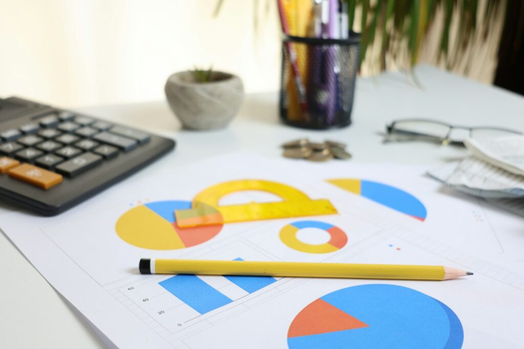CFO Aufgaben im Alltag: Schreibtisch mit Taschenrechner, Diagrammen und Bleistift