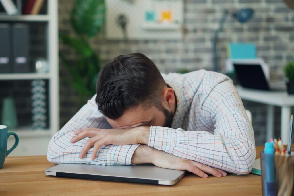Erschöpfter Mann im Anzug am Schreibtisch – fehlendes Energiemanagement im Führungsalltag