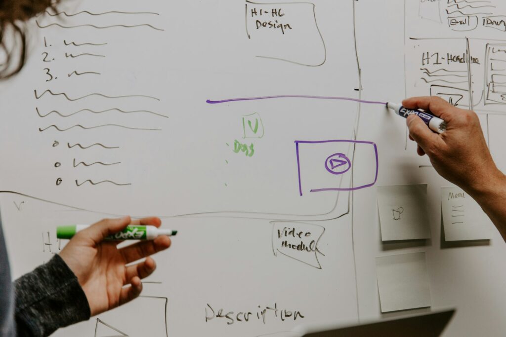 Zwei Personen skizzieren Risiken auf einem Whiteboard als Pre-Mortem für Entscheidungen unter Unsicherheit