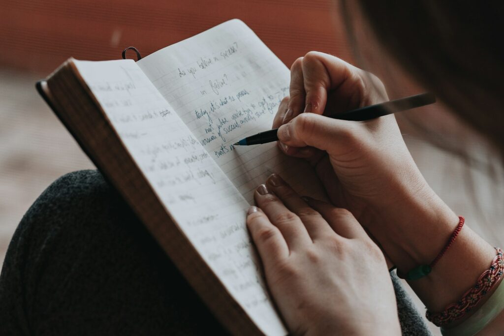 Frau notiert Annahmen in einem Notizbuch als Entscheidungsjournal für Entscheidungen unter Unsicherheit