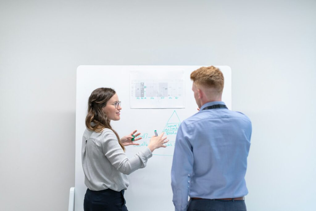 Zwei Kollegen entwickeln am Whiteboard ein gemeinsames Bild – laterale Führung durch Verständigung