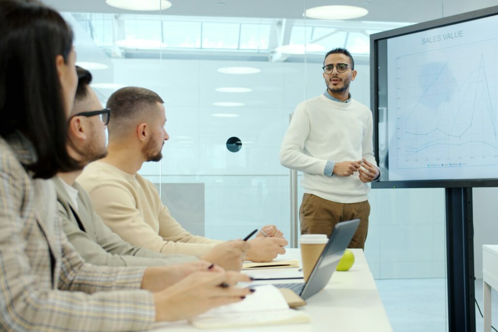 Management-KPIs präsentieren: Mann erläutert Diagramme vor Kolleginnen und Kollegen im Meeting