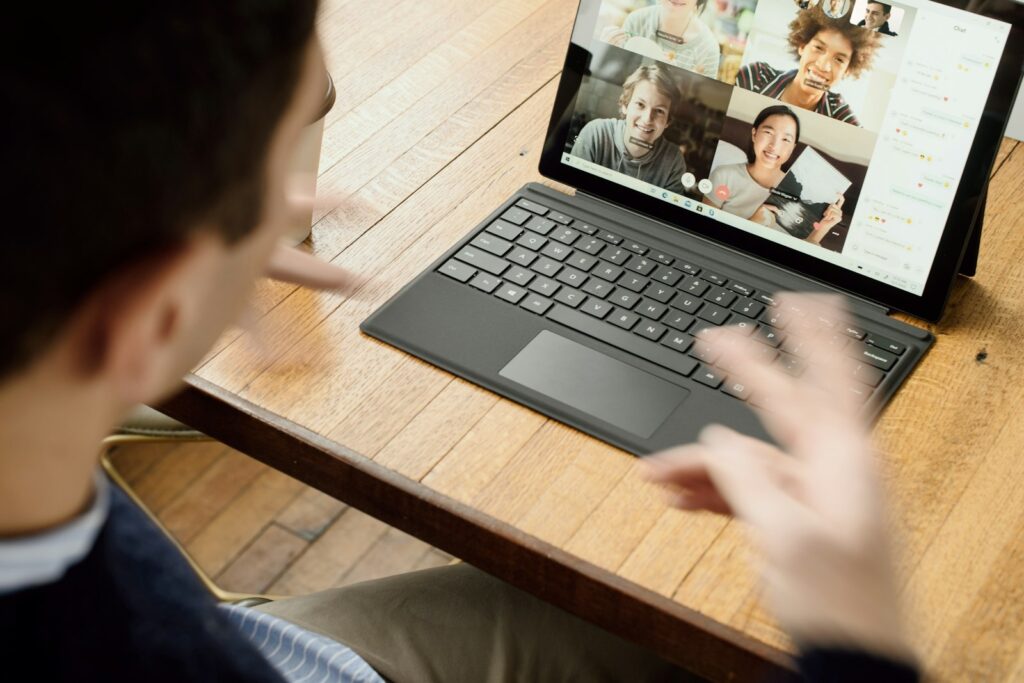 Teammitglied am Laptop im Austausch mit Kollegen – Remote Leadership schafft Nähe auf Distanz