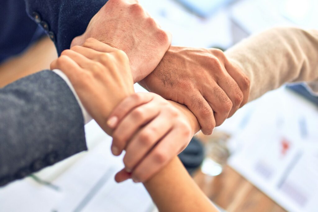 Team hält sich in einer Geste der Verbundenheit an den Handgelenken, Symbol für Vertrauen im Team