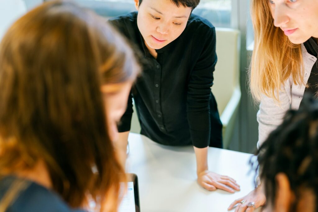 Vier Personen prüfen gemeinsam Unterlagen am Tisch und bauen Vertrauen im Team wieder auf